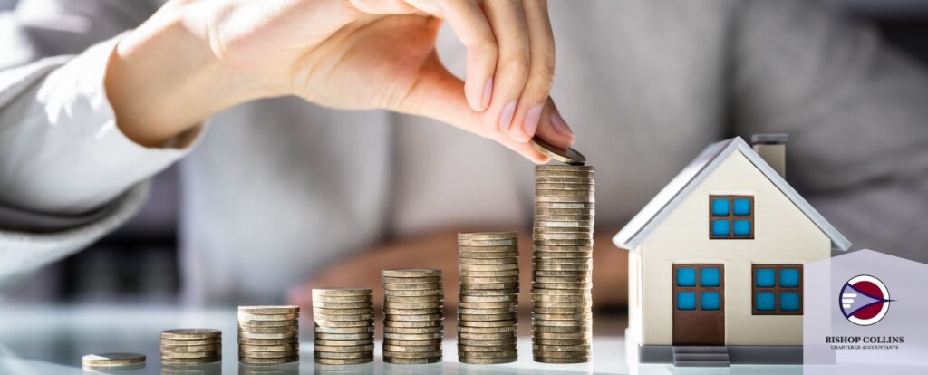 Person stacking coins near model house