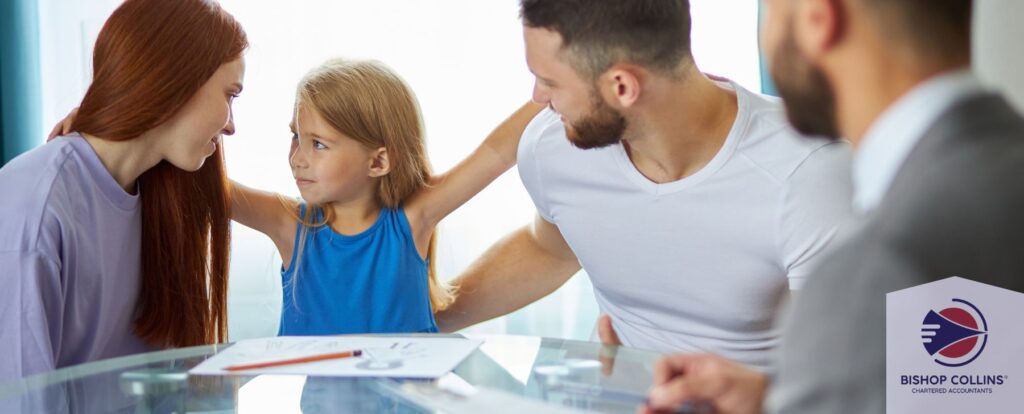 A man and woman look at their child as a professional signs papers on the glass table