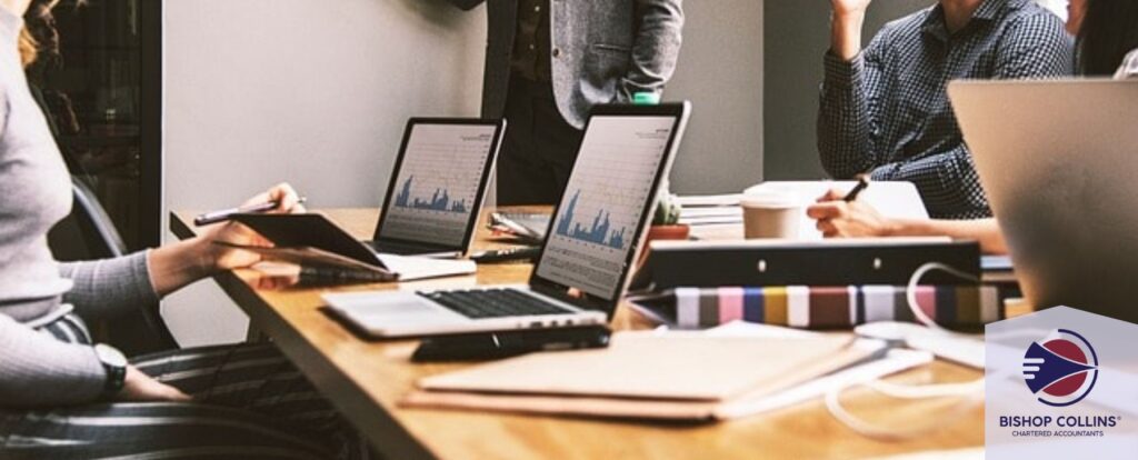 Team of tax accountants in an office meeting reviewing data on laptops