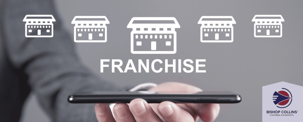 Header -the word franchise sits on top of a business arm holding a phone horizontally. There are 5 different sized emoji's of shop fronts on top to demonstrate a franchise. The Bishop Collins Chartered Accountants logo is in the bottom right corner.